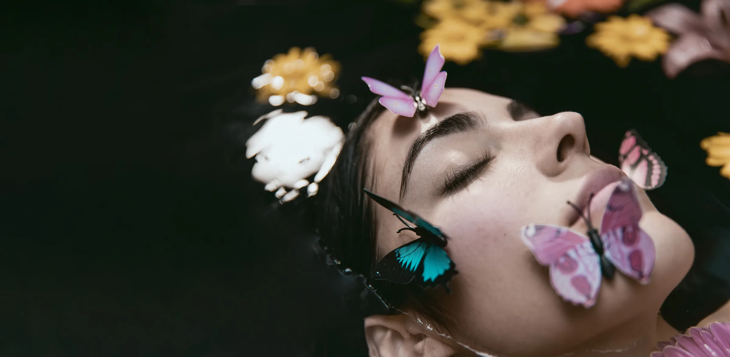 A woman resting in water surrounded by flowers and butterflies