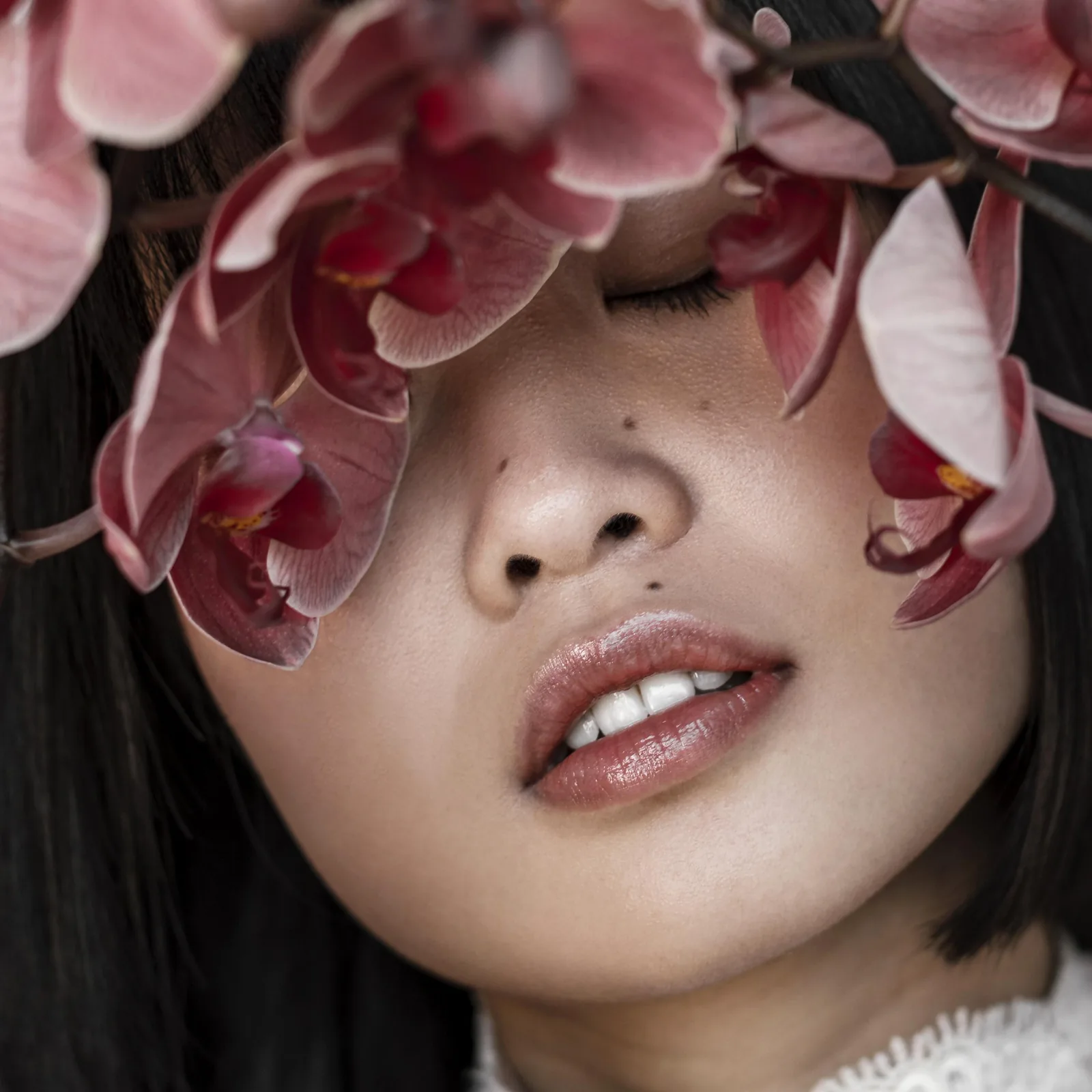 A woman's face framed by pink orchids